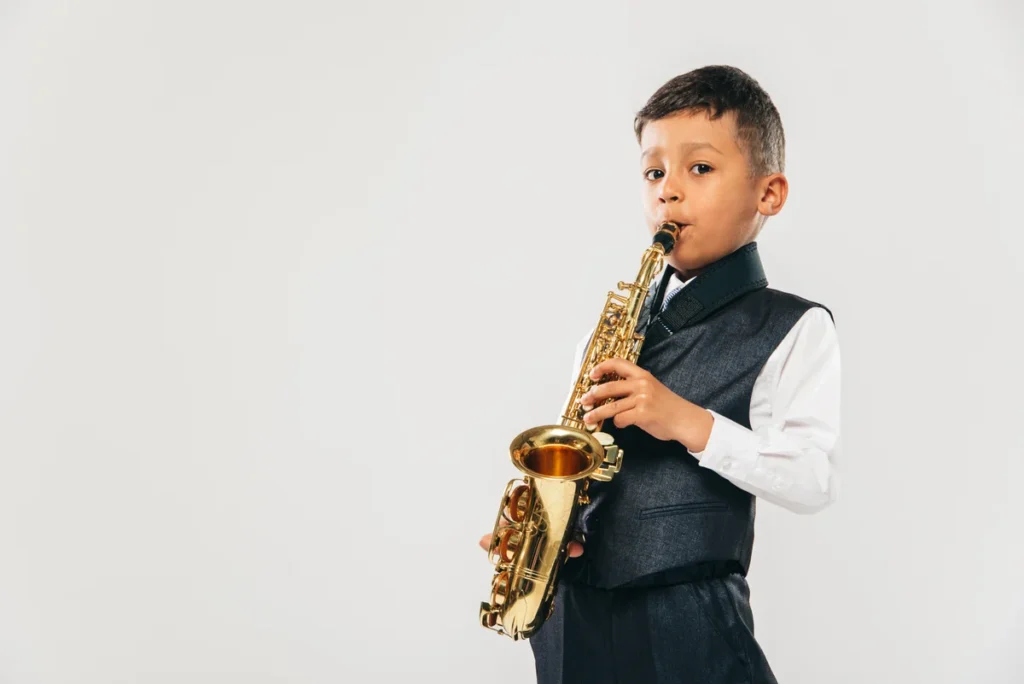 # Qual tipo de aluno de saxofone é você? Conheça 8 perfis e descubra como estudar melhor

**Qual tipo de aluno de saxofone é você?** Cada pessoa aprende de uma maneira diferente. Alguns alunos adoram exercícios, outros só querem tocar músicas, alguns estudam todos os dias e outros aproveitam os momentos livres.

Nenhum desses estilos é necessariamente certo ou errado.

O importante é entender **quais são as vantagens do seu jeito de estudar e quais comportamentos podem estar atrapalhando sua evolução**.

Afinal, conhecer seu próprio perfil pode ajudar você a estudar de maneira mais inteligente.

## 🔥 1. O aluno empolgado

Você acabou de começar a estudar sax e quer aprender tudo.

Uma música nova? Você quer tocar.

Uma escala? Quer aprender.

Improvisação? Também.

Técnica avançada? Por que não? 😂

### A vantagem

A empolgação é uma grande aliada no começo. Você tem curiosidade, vontade de experimentar e provavelmente não precisa de muito esforço para pegar o saxofone e estudar.

### O problema

O excesso de entusiasmo pode fazer você começar muitas coisas e terminar poucas.

Você pode passar uma semana estudando cinco músicas diferentes, três exercícios e duas técnicas, mas sem desenvolver nenhuma delas de verdade.

### Como tirar o máximo proveito

Aproveite sua curiosidade, mas coloque limites.

Escolha **uma ou duas prioridades por vez** e mantenha algumas coisas novas apenas como complemento.

Assim, você continua explorando o sax sem transformar seu estudo em uma coleção de coisas começadas e abandonadas.

---

## 🐢 2. O aluno paciente

Esse aluno prefere aprender devagar.

Ele gosta de repetir bastante uma música ou exercício antes de passar para algo novo, porque quer sentir que realmente entendeu o que está fazendo.

### A vantagem

Essa paciência pode ajudar bastante na construção de uma base sólida.

Você provavelmente não tem tanta pressa para avançar e pode prestar atenção aos detalhes que outros alunos deixam passar.

### O problema

Às vezes, a busca por segurança pode virar medo de avançar.

Você pode pensar:

“Só vou começar a próxima música quando conseguir tocar essa perfeitamente.”

O problema é que talvez você nunca sinta que está perfeito.

### Como tirar o máximo proveito

Continue valorizando a repetição, mas estabeleça critérios realistas para avançar.

Você não precisa dominar uma música 100% antes de começar outra.

Aprender algo novo também pode ajudar a desenvolver habilidades que estavam faltando naquilo que você já estudava.

---

## 🎵 3. O aluno que só quer tocar músicas

Você não vê a hora de aprender aquela música que gosta.

Escalas?

“Depois eu vejo.”

Exercícios?

“Preciso mesmo?”

Você quer colocar o sax na boca e tocar música. 😂

### A vantagem

Esse perfil costuma ter uma motivação muito forte.

Você tem um motivo concreto para aprender sax: **quer tocar músicas que gosta.**

Isso pode tornar o estudo muito mais prazeroso.

### O problema

Se você estudar apenas as músicas que gosta, pode acabar evitando justamente os exercícios que desenvolveriam suas dificuldades.

A música pode exigir uma técnica que você ainda não domina, mas simplesmente repetir a música não significa necessariamente que essa técnica vai melhorar.

### Como tirar o máximo proveito

Use as músicas como ferramentas de estudo.

Encontrou uma passagem difícil?

Em vez de simplesmente pular, descubra o que está dificultando aquela parte.

Talvez seja ritmo, digitação, articulação ou respiração.

Assim, você continua fazendo aquilo que gosta e, ao mesmo tempo, transforma a música em um exercício.

---

## 📚 4. O aluno estudioso

Você gosta de entender tudo.

Quer saber quais são as escalas, como funciona a teoria, por que determinada nota funciona, como melhorar a técnica e qual exercício deve praticar.

### A vantagem

Esse perfil pode desenvolver uma excelente consciência sobre o próprio aprendizado.

Você não está simplesmente repetindo movimentos; está tentando entender o que está fazendo.

### O problema

Existe o risco de transformar o estudo em teoria demais e música de menos.

Você pode passar tanto tempo estudando sobre como tocar que acaba tocando pouco.

### Como tirar o máximo proveito

Use o conhecimento para melhorar sua prática.

Aprendeu algo novo?

Pegue o sax e experimente.

Descobriu uma escala?

Use-a em uma música ou improvisação.

Entendeu uma técnica?

Observe como ela funciona na prática.

**Conhecimento deve voltar para o instrumento.**

---

## 🎧 5. O aluno imitador

Você tem um saxofonista favorito e quer tocar como ele.

Escuta as gravações, tenta copiar o som, o fraseado, o vibrato e até pequenas características da maneira como ele toca.

### A vantagem

Imitar bons músicos pode ser uma excelente ferramenta de aprendizado.

Você começa a desenvolver o ouvido e percebe detalhes que talvez não percebesse apenas olhando uma partitura.

### O problema

Se você passar tempo demais tentando reproduzir outra pessoa, pode esquecer de descobrir sua própria identidade musical.

### Como tirar o máximo proveito

Use seus ídolos como professores, não como modelos que você precisa copiar para sempre.

Tente reproduzir uma frase.

Depois toque a mesma frase de outra maneira.

Experimente diferentes articulações, dinâmicas e formas de interpretar.

**Primeiro você aprende observando os outros; com o tempo, começa a descobrir o que quer fazer com aquilo que aprendeu.**

---

## 💪 6. O aluno teimoso

Você encontrou uma passagem difícil?

Então agora é questão de honra.

Você tenta uma vez.

Erra.

Tenta novamente.

Erra de novo.

Mais uma vez.

E outra.

### A vantagem

Persistência é uma das características mais importantes para quem aprende um instrumento.

Você não abandona facilmente uma dificuldade.

### O problema

Existe uma diferença entre **persistir** e **repetir o mesmo erro várias vezes.**

Se você toca uma passagem dez vezes exatamente da mesma maneira e erra sempre no mesmo lugar, talvez não precise de mais dez tentativas.

Precisa descobrir o que está causando o erro.

### Como tirar o máximo proveito

Quando uma passagem não sair, pare e investigue.

Pergunte:

* O problema está na digitação?
* O ritmo está errado?
* A articulação está atrapalhando?
* Estou tentando tocar rápido demais?
* Preciso dividir a passagem em partes menores?

Depois mude a estratégia e tente novamente.

**Persistência é continuar tentando; inteligência é descobrir como tentar melhor.**

---

## 😎 7. O aluno que aprende de ouvido

Você escuta uma música e tenta descobrir as notas sozinho.

Talvez consiga reproduzir melodias sem olhar a partitura e tenha facilidade para perceber diferenças entre os sons.

### A vantagem

Esse hábito pode desenvolver bastante sua percepção auditiva.

Você aprende a ouvir antes de pensar na representação escrita da música.

### O problema

Se depender somente do ouvido, você pode encontrar dificuldades quando precisar ler partituras, compreender determinadas estruturas ou aprender músicas que não consegue ouvir com facilidade.

### Como tirar o máximo proveito

Não abandone seu ouvido.

Use-o como uma das suas principais ferramentas, mas desenvolva também a leitura.

Uma boa combinação pode ser ouvir uma melodia, tentar reproduzi-la e depois conferir como ela aparece na partitura.

Assim, você começa a conectar **o que ouve com o que vê e toca.**

---

## ⏰ 8. O aluno “quando dá”

Sua rotina é corrida.

Nem sempre você consegue estudar no mesmo horário e talvez alguns dias passem sem que você consiga pegar no sax.

### A vantagem

Você provavelmente é bom em aproveitar oportunidades.

Quando aparece um espaço na rotina, consegue estudar.

### O problema

Se o estudo depender exclusivamente de “quando der”, é fácil passar vários dias sem praticar.

E a falta de regularidade pode dificultar a evolução.

### Como tirar o máximo proveito

Você não precisa necessariamente estudar durante horas todos os dias.

Tente estabelecer **um mínimo possível de manter**.

Pode ser uma quantidade pequena de tempo em determinados dias da semana.

Quando tiver mais tempo, você estuda mais.

Quando tiver menos, faz o mínimo.

O objetivo é criar alguma regularidade sem transformar o estudo em uma obrigação impossível de cumprir.

---

# 🧩 Afinal, qual tipo de aluno você é?

Provavelmente mais de um.

Você pode ser empolgado e, ao mesmo tempo, gostar de aprender de ouvido.

Pode ser estudioso, mas também querer tocar apenas suas músicas favoritas.

Pode ser paciente em algumas situações e extremamente teimoso em outras. 😂

Esses perfis não são caixas definitivas.

Eles são apenas **formas de observar seus próprios hábitos de estudo.**

E isso é o que realmente importa.

## 🎯 Como tirar o máximo proveito do seu perfil?

Depois de descobrir com qual perfil você mais se identifica, faça duas perguntas:

**“Qual característica minha está ajudando minha evolução?”**

E:

**“Qual característica pode estar me atrapalhando?”**

Depois, tente manter a primeira e ajustar a segunda.

Se você é muito empolgado, não precisa perder sua curiosidade. Apenas aprenda a organizar suas prioridades.

Se só gosta de músicas, não precisa abandonar as músicas. Use-as para trabalhar suas dificuldades.

Se é teimoso, não precisa desistir quando algo fica difícil. Aprenda apenas a mudar de estratégia quando a repetição não estiver funcionando.

Se é perfeccionista, não precisa aceitar qualquer coisa. Apenas entenda quando é hora de continuar avançando.

**Seu jeito de aprender não precisa ser um obstáculo. Ele pode se tornar uma ferramenta.**

No final, não existe um único tipo de aluno que consiga aprender saxofone.

Existem pessoas diferentes, com dificuldades diferentes, motivações diferentes e maneiras diferentes de aprender.

O objetivo não é descobrir qual perfil é “o melhor”.

É descobrir **como usar aquilo que você já tem a seu favor e corrigir aquilo que está impedindo sua evolução.** 🎷
